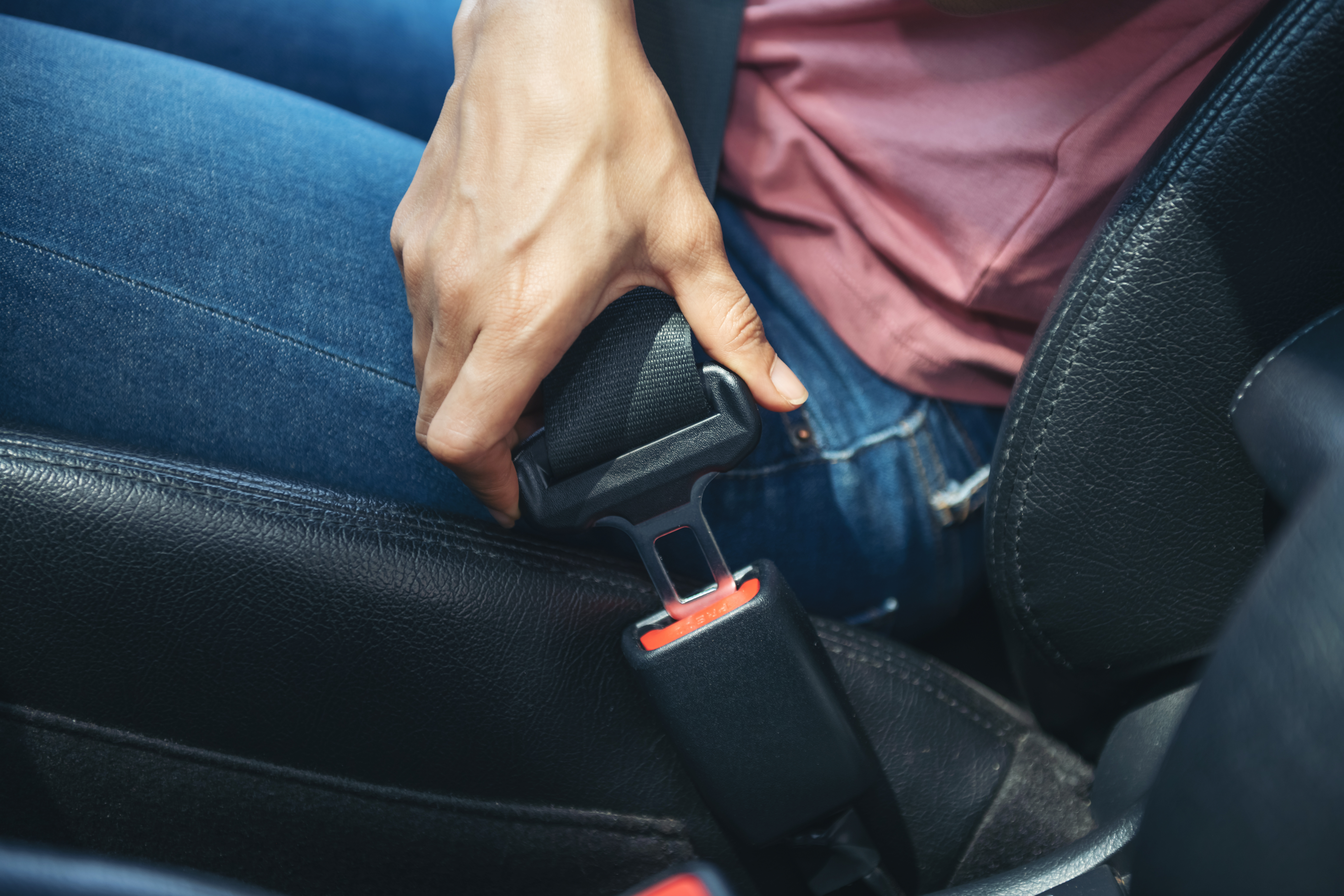 woman hand fastening seatbelt car cropped image woman sitting car putting her seat belt safe driving concept